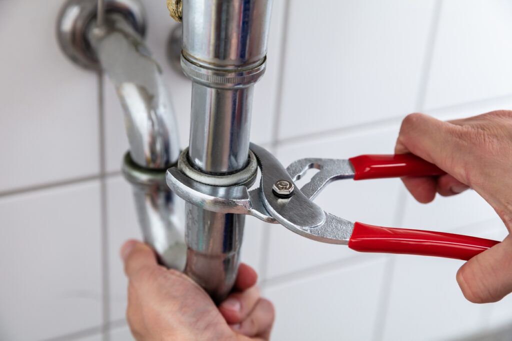 Close-up Of A Plumber's Hand Repairing Sink With Adjustable Wrench